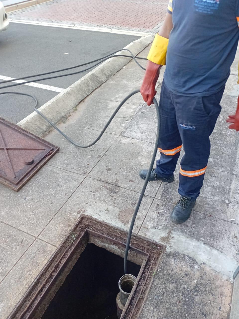 Drain camera cable lowered into an open manhole